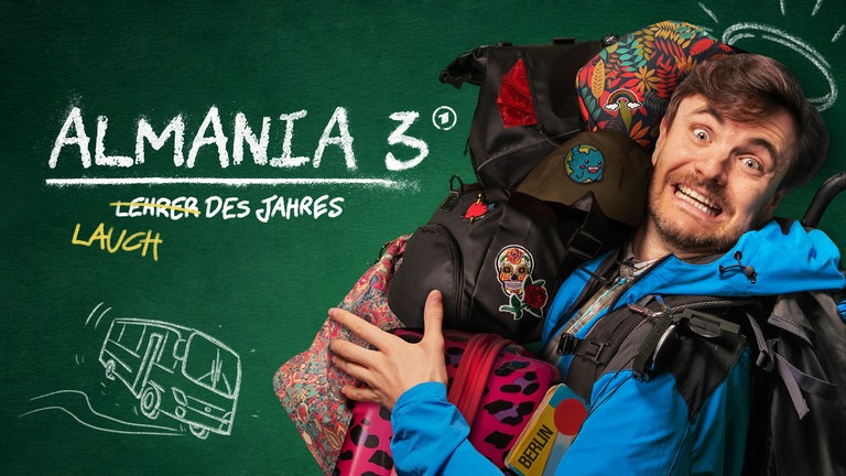 Phil Laude aus der Comedy-Serie "Almania" voll bepackt mit Rucksäcken vor einer vollgekritzelten Tafel