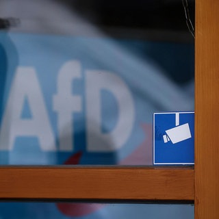 Das Logo der AfD ist hinter einem Fenster zu sehen.