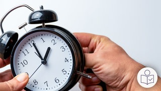 Zwei Hände mit einem schwarzen Wecker. Der Wecker steht auf 2 Uhr. Die Hände verstellen den Wecker. Rechts das SWR Logo für Leichte Sprache.