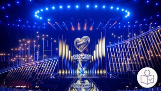 Die Bühne von dem ESC 2026 in Wien. Viele Lichter leuchten auf die Bühne. Rechts das SWR Logo für Leichte Sprache.
