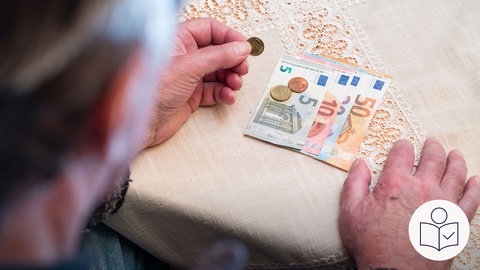 Geld liegt auf einem Tisch. Eine Hand hält eine Geld·münze. Rechts das SWR Logo für Leichte Sprache. 