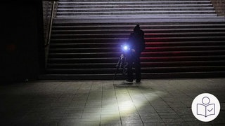 Ein Mann geht mit seinem Fahrrad durch den Bahnhof Wannsee nach einem Strom·ausfall in Berlin. Rechts das SWR Logo für Leichte Sprache.