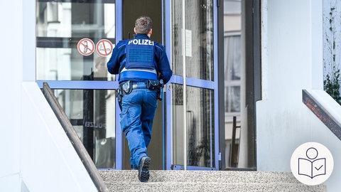 Ein Polizist von hinten. Er geht Treppen hoch und durch eine blaue Tür. Die Tür ist der Eingang von einer Schule in Ludwigshafen. Rechts das SWR Logo für Leichte Sprache.