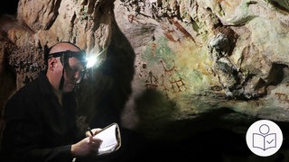 Ein Forscher steht in einer Höhle. Er hat eine Stirnlampe auf dem Kopf. An der Felswand sind Malereien in roter Farbe. Rechts das Logo für Leichte Sprache