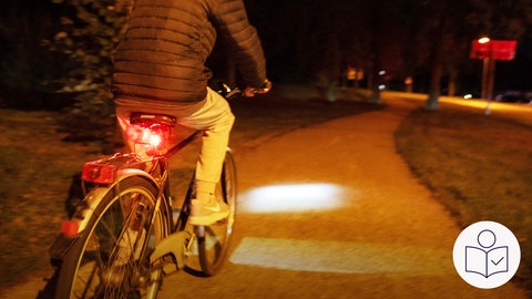 Ein Mann auf einem Fahrrad. Er fährt einen Radweg entlang. Man sieht den Radfahrer von hinten. Es ist dunkel. Aber das Fahrrad hat Licht. Es gibt immer mehr Unfälle mit betrunkenen Radfahrern. Rechts das SWR Logo für Leichte Sprache.