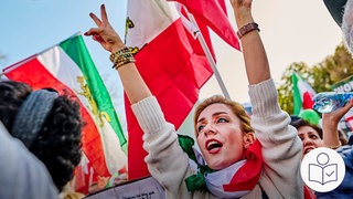 Eine Frau auf einer Demonstration streckt die Arme in die Luft. Im Hintergrund sind iranische Flaggen. Frauen protestieren für Gleich·berechtigung. Rechts das SWR Logo für Leichte Sprache.
