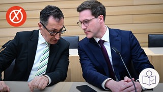 Links sitzt Cem Özdemir von den Grünen. Neben ihm sitzt Manuel Hagel von der CDU. Die beiden reden miteinander. Rechts das SWR Logo für Leichte Sprache. Links oben ein roter Kreis mit einem weißen Kreuz.