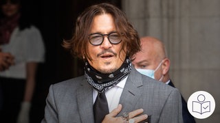 Der Schauspieler und Künstler Johnny Depp. Er hält eine Hand vor seine Brust. Auf der Hand hat er Tattoos. Gemälde von Johnny Depp sind jetzt in Emmendingen ausgestellt. Rechts das SWR Logo für Leichte Sprache.