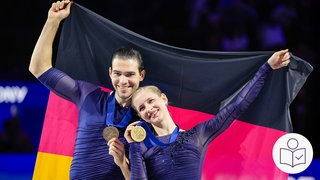 Nikita Volodin und Minerva Hase stehen nebeneinander. Beide haben eine Gold·medaille um den Hals. Mit einer Hand hält jeder seine Gold·medaille fest. Mit der anderen Hand halten sie eine große Deutschland·fahne hinter sich. Rechts das SWR Logo für Leichte Sprache.