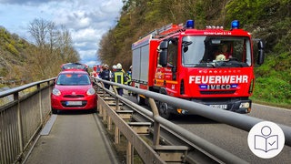 Ein rotes Auto steht auf einem schmalen Rad∙weg. Links ist ein Geländer, rechts die Leit∙planke zur Straße hin. Ganz rechts auf der Straße steht ein Feuerwehr∙auto. Rechts unten das SWR Logo für Leichte Sprache.  