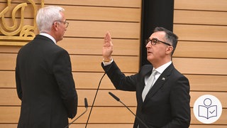 Rechts Cem Özedemir bei seiner Vereidigung zum Minister·präsidenten. Der Landtag in Baden-Württemberg hat Cem Özdemir gewählt. Links steht der Landtags·präsident Thomas Strobl. Rechts das SWR Logo für Leichte Sprache.