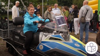 Eine Frau sitzt auf einem Schnee·mobil. Das Schnee·mobil ist von der Polizei. Die Polizei in Freiburg hat Menschen mit Behinderung zu einem Besuchs·tag eingeladen. Rechts das SWR Logo für Leichte Sprache.
