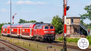 Ein roter Zug der Deutschen Bahn. Der Zug fährt auf Gleisen. Daneben sieht man ein altes Gebäude. Rechts das SWR Logo für Leichte Sprache.