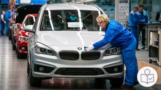 Eine Frau an einem Fließband bei BMW poliert die Front eines Autos. Rechts unten das SWR-Logo für Leichte Sprache.