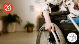 Das ist ein Beispiel·bild. Eine Frau sitzt in einem Rollstuhl. Man sieht nur ein Teil von dem Rollstuhl und der Frau. Im Hintergrund ist eine Wohnung. Links oben ist ein roter Kreis mit einem weißen Kreuz. Rechts das SWR Logo für Leichte Sprache.