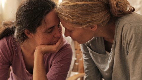 Zwei Frauen lehnen sich zärtlich aneinander an