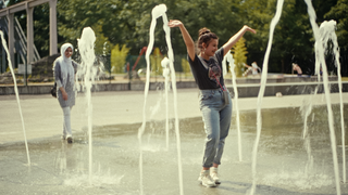Zwei Teenagerinnen laufen durch einen Springbrunnen