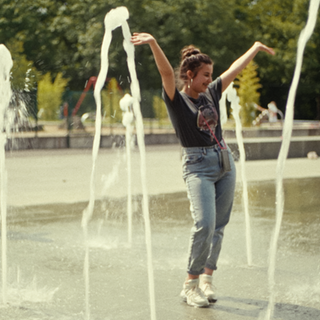 Zwei Teenagerinnen laufen durch einen Springbrunnen