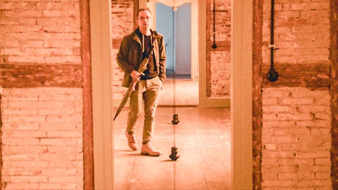 Mann mit Regenschirm bewegt sich in einem Ausstellungsraum