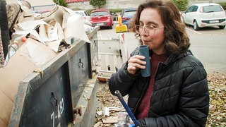 Kate Carr von Rubbish Music bläst in ein Rohrstück aus einem Müllcontainer