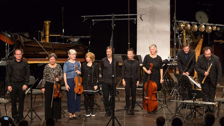 Neun MusikerInnen auf der Bühne beim Schlussapplaus nach dem Konzert im Bartok Saal