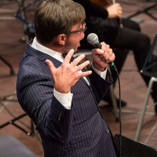Mann mit Anzug singt ins Mikrophon