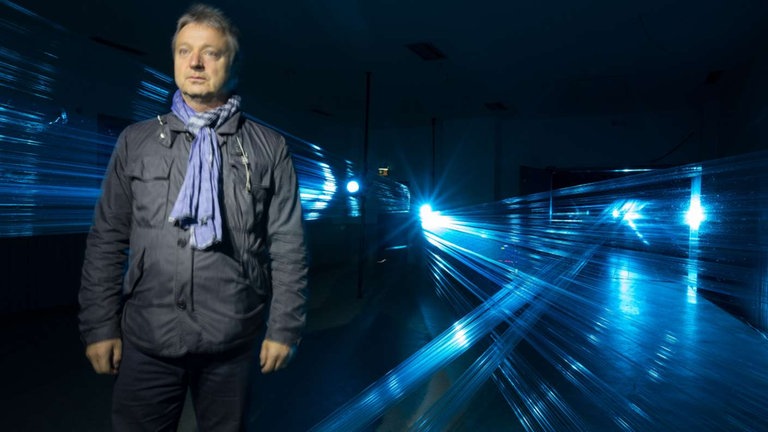 Mann in Parka und Schal im Projektorlicht