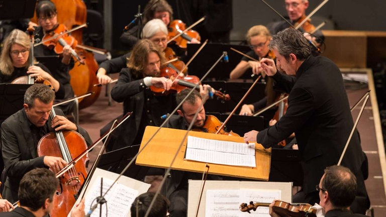 Mann in Schwarz dirigiert Orchester