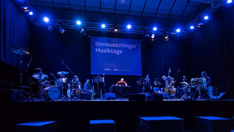 Sieben musiker auf der Bühne bei der NOWJazz-Session in der Sporthalle der Gewerbeschulen