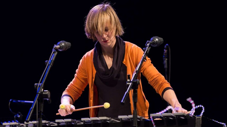 Frau spielt Vibraphon mit gelben Schlägeln bei der NOWJazz-Session in der Sporthalle der Gewerbeschulen