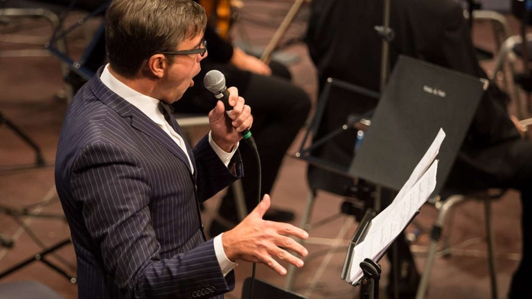 Mann im Anzug singt ins Mikrophon