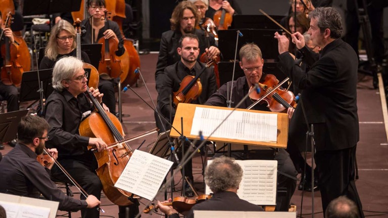 Mann dirigiert Streichquartett und Orchester