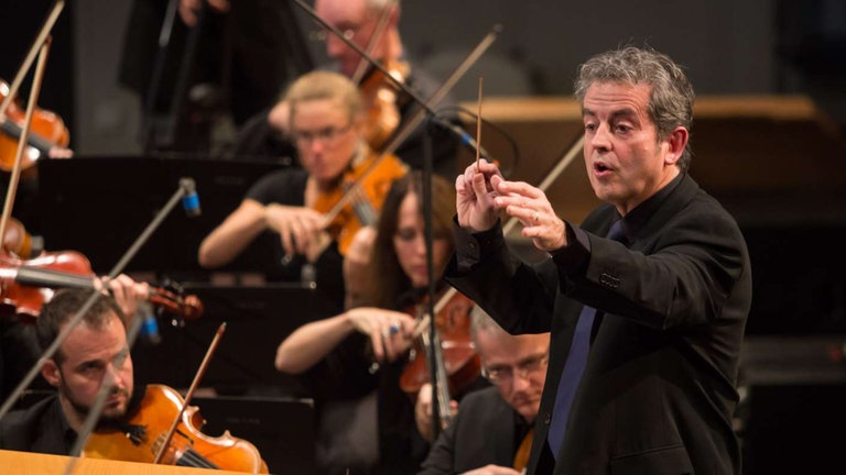Mann dirigert Orchester beim Eröffnungskonzert