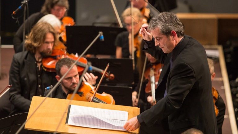 Mann, der Orchester leitet, schaut beim Eröffnungskonzert in Partitur