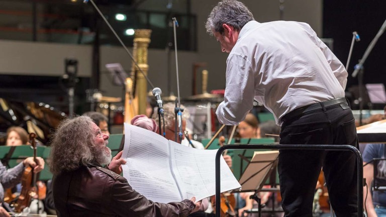 DIrigent mit Komponist über Partitur im Gespräch bei Proben zum Eröffnungskonzert
