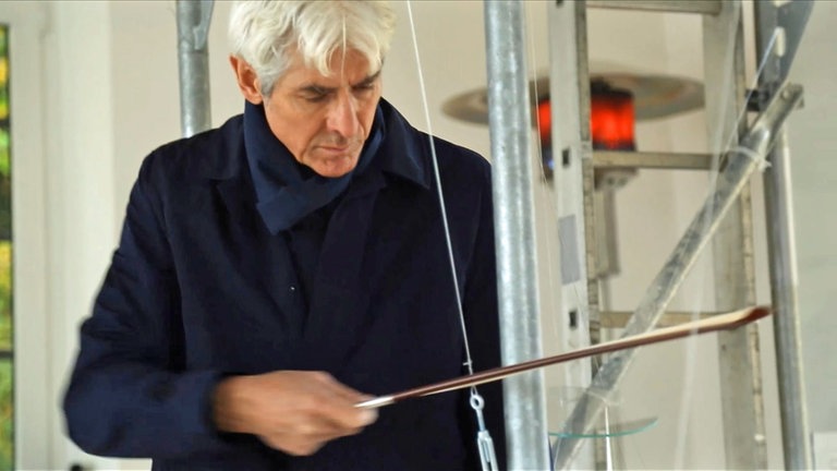 Mann spielt auf selbst entwickeltem Streichinstrument
