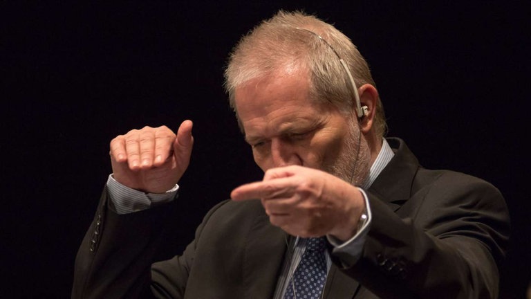 Mann mit Bart hat Hände zum Dirigieren erhoben