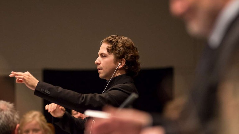 Junger Mann dirgiert Orchester