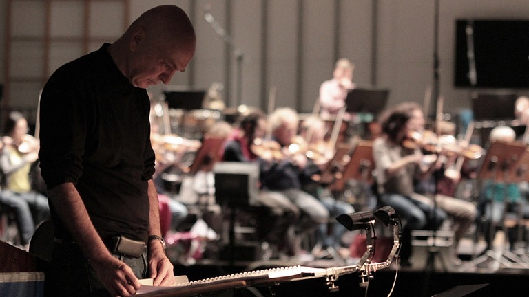 Der Komponist Bernhard Lang schaut stehend in seine Partitur