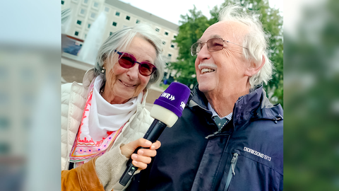 Tici interviewt die Eheleute Helen und Klaus-Peter zum Thema Liebe. Helen und Klaus-Peter lachen in die Kamera. 
