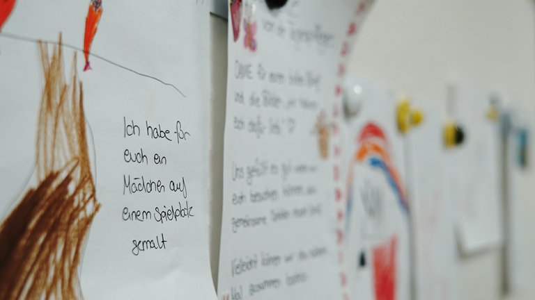 Zeichnungen von Kindern, die an der Wand hängen. 