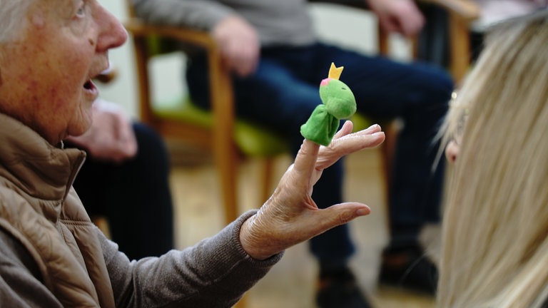 Ältere Dame zeigt eine Fingerpuppe in Form einer Schlange.