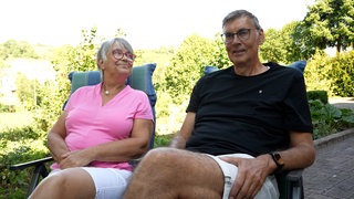 Mann und Frau sitzen auf ihren Gartenstühlen.