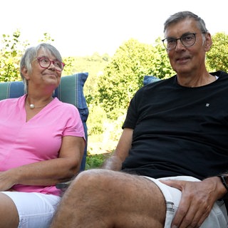 Mann und Frau sitzen auf ihren Gartenstühlen.