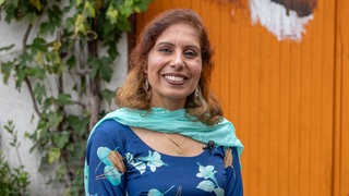 Frau mit blauem Schal lächelt in die Kamera.