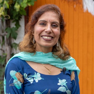 Frau mit blauem Schal lächelt in die Kamera.