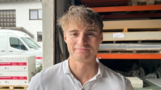 Junger Mann mit blonden strubbeligen Haaren im Polohemd.