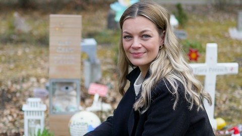 Laura kniet am Waldfriedhof neben dem Grab ihres Sternenkinds Luan.