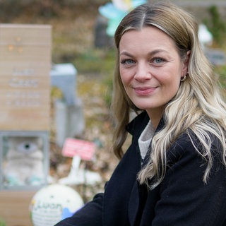 Laura kniet am Waldfriedhof neben dem Grab ihres Sternenkinds Luan.