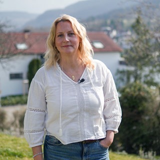Christine steht bei sich zu Hause im Garten und schaut in die Kamera. Hinter ihr ist die schwäbische Alb zu sehen. Der Garten war ihr Kraftort, als sie stark unter Panikattacken gelitten hat. 